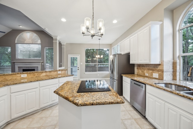 kitchen with white cabinets, appliances with stainless steel finishes, an inviting chandelier, backsplash, and a kitchen island