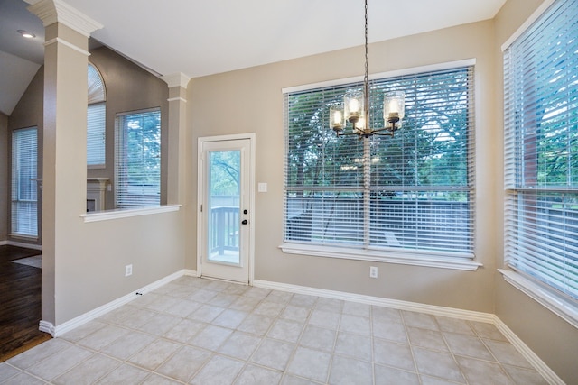 unfurnished dining area with ornate columns, baseboards, a chandelier, and tile patterned floors