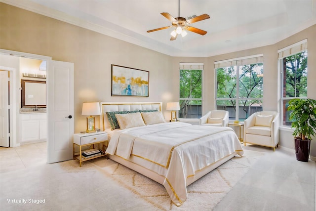 bedroom featuring ensuite bathroom, a sink, a raised ceiling, and multiple windows