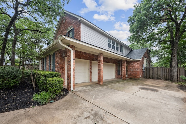 view of property exterior featuring fence, an attached garage, driveway, and brick siding