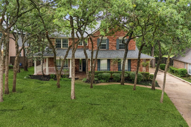 view of front of home featuring concrete driveway, brick siding, covered porch, and a front lawn
