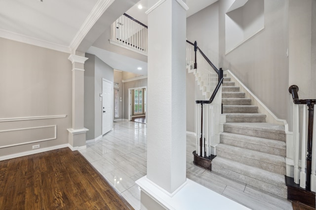 staircase featuring ornate columns, ornamental molding, baseboards, and wood finished floors