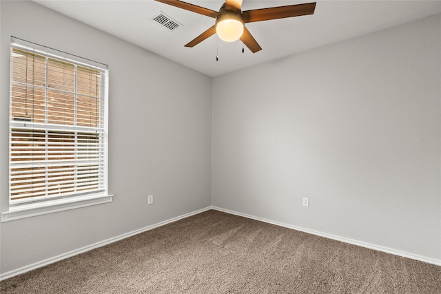carpeted empty room with visible vents, a ceiling fan, and baseboards