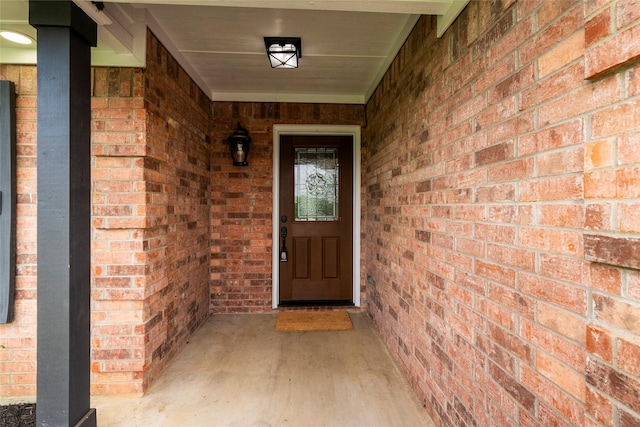 property entrance with a porch and brick siding