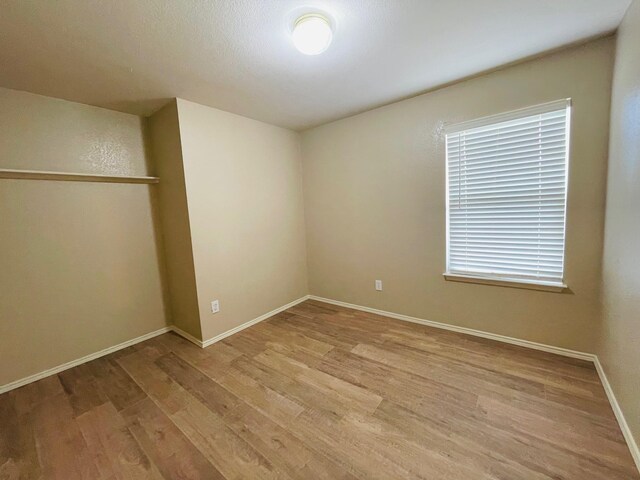 spare room featuring baseboards and light wood finished floors