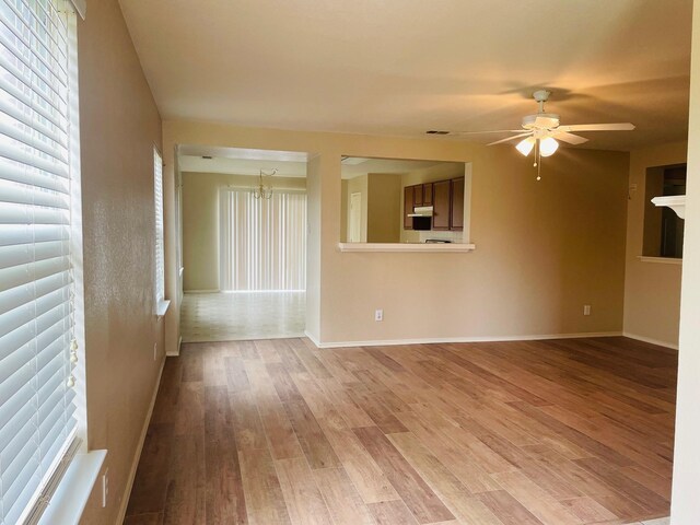 empty room with a ceiling fan, baseboards, and light wood-style flooring