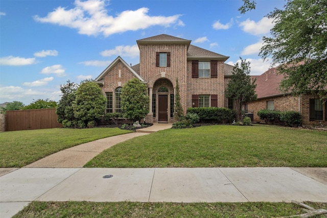 traditional-style home featuring fence, a front lawn, and brick siding