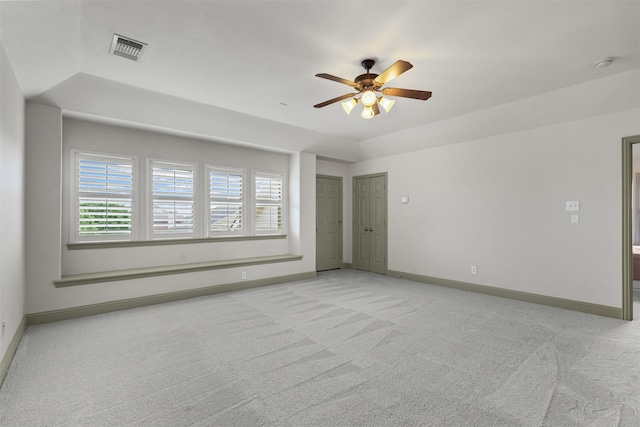 unfurnished room featuring a tray ceiling, light colored carpet, and visible vents