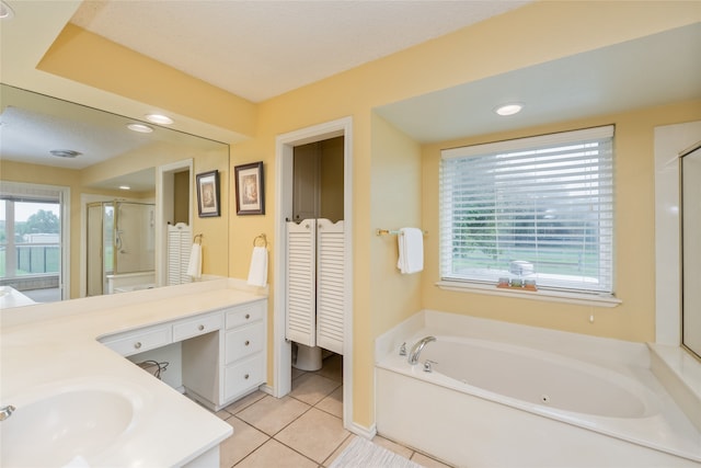 bathroom featuring tile patterned flooring, vanity, a shower stall, a garden tub, and a closet