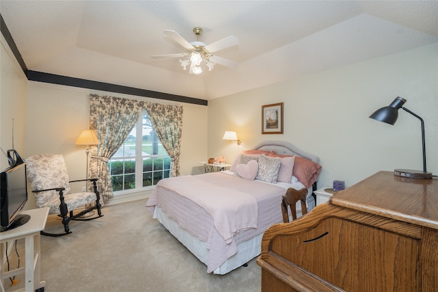 carpeted bedroom featuring ceiling fan and a tray ceiling