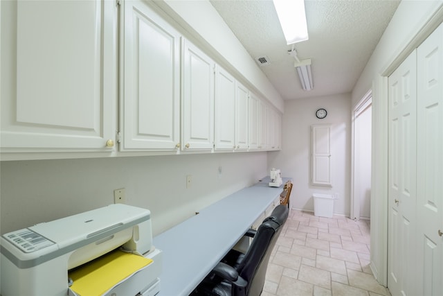 laundry area featuring stone finish floor, baseboards, a textured ceiling, and visible vents