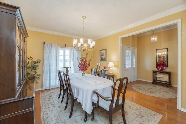 dining space with crown molding, plenty of natural light, light wood-type flooring, and a chandelier