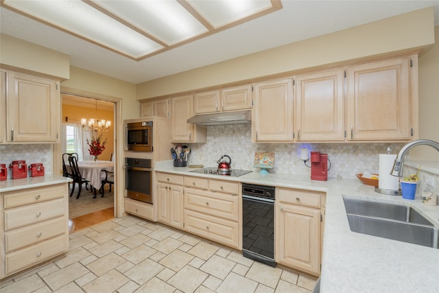 kitchen featuring light brown cabinets, light countertops, under cabinet range hood, a sink, and appliances with stainless steel finishes
