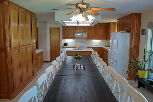 6928 Scott St, Eustace, TX 75124 - kitchen featuring white appliances, ceiling fan, light countertops, brown cabinetry, and a center island