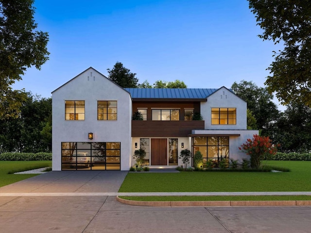 view of front of property with stucco siding, driveway, a front lawn, and a garage