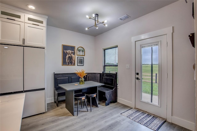 dining space with light wood-style floors, baseboards, visible vents, and a chandelier
