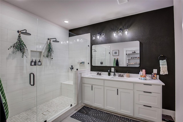 full bathroom with double vanity, a sink, a stall shower, and visible vents