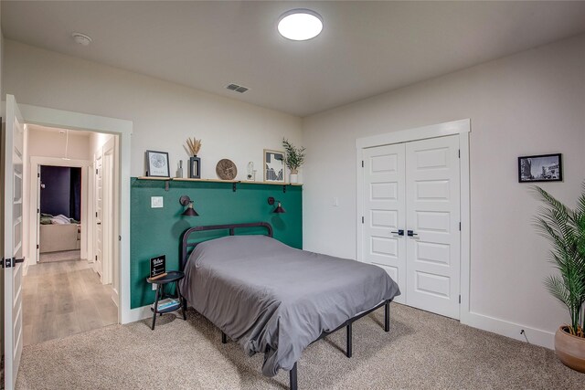 bedroom with baseboards, light carpet, a closet, and visible vents