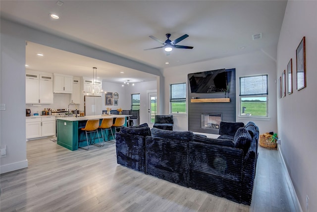 living room featuring visible vents, baseboards, recessed lighting, light wood-type flooring, and ceiling fan with notable chandelier