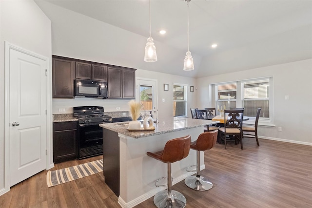 1421 Avalon Ct, Celina, TX 75009 - kitchen featuring black appliances, vaulted ceiling, dark wood-style floors, healthy amount of natural light, and light stone countertops