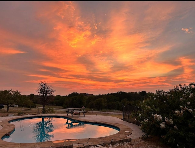 pool at dusk featuring a patio and an outdoor pool