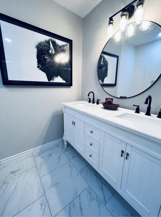 bathroom with baseboards, a sink, marble finish floor, and double vanity