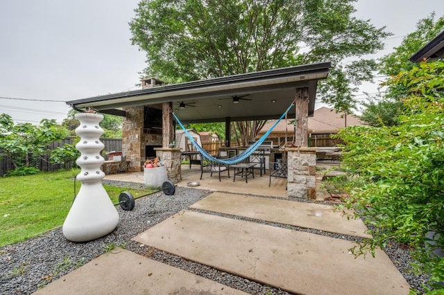 view of patio / terrace with an outdoor stone fireplace, ceiling fan, and a fenced backyard