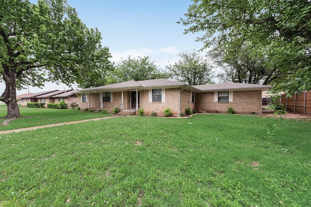 ranch-style home with brick siding, fence, and a front lawn