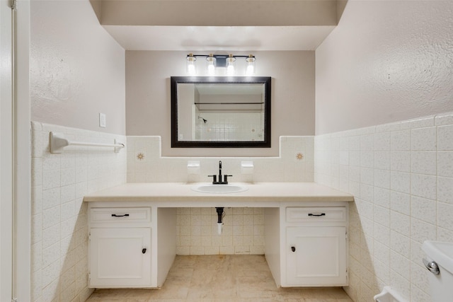 bathroom featuring a wainscoted wall, a sink, tile patterned floors, and tile walls