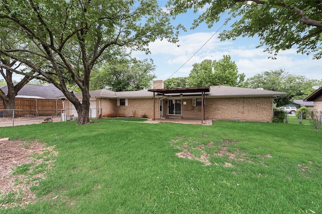 back of house featuring brick siding, a chimney, a yard, and fence private yard