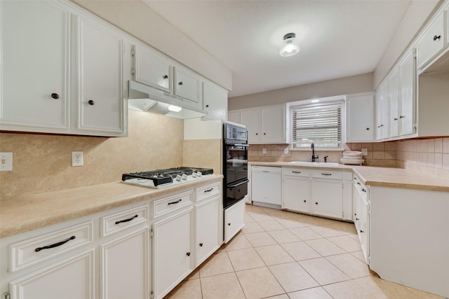 kitchen with a sink, under cabinet range hood, white appliances, and tasteful backsplash