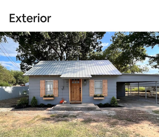 view of front of house featuring fence, metal roof, and a carport