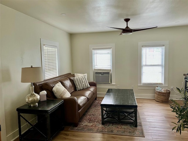 living area featuring baseboards, a ceiling fan, wood finished floors, and cooling unit