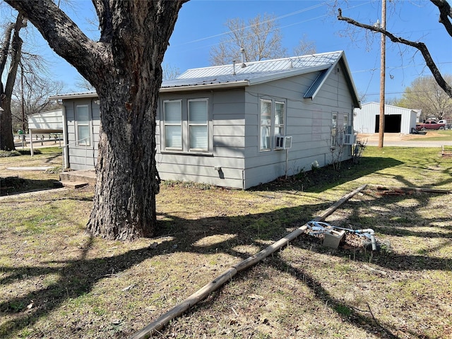 view of home's exterior featuring a lawn, cooling unit, and metal roof