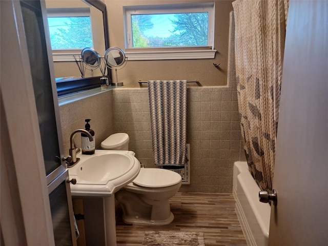 9528 Ash Creek Dr, Dallas, TX 75228 - bathroom with wainscoting, wood finished floors, toilet, tile walls, and a sink