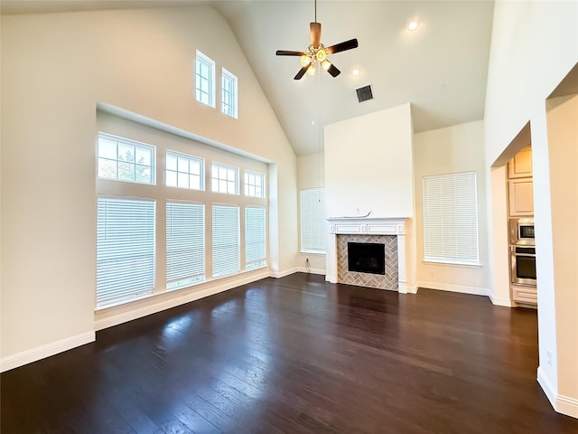 6900 Royal Liverpool Dr, Mckinney, TX 75070 - unfurnished living room with ceiling fan, a tiled fireplace, high vaulted ceiling, baseboards, and dark wood-style floors