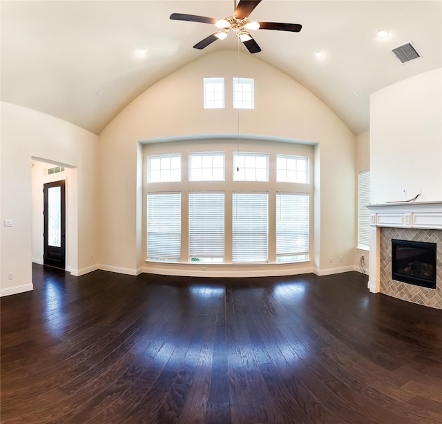 6900 Royal Liverpool Dr, Mckinney, TX 75070 - unfurnished living room featuring a ceiling fan, visible vents, a tiled fireplace, vaulted ceiling, and hardwood / wood-style floors