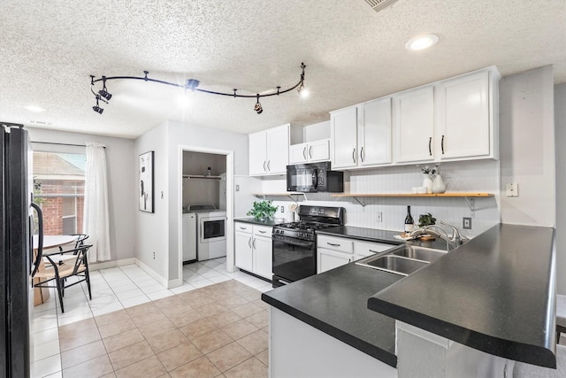 kitchen featuring washer and dryer, dark countertops, a sink, rail lighting, and black appliances
