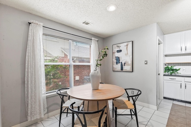 dining room featuring light tile patterned floors, a textured ceiling, visible vents, and baseboards