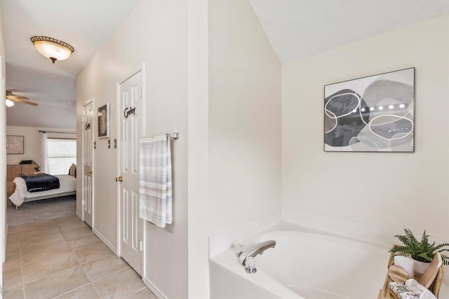 ensuite bathroom featuring a ceiling fan, a bath, tile patterned flooring, vaulted ceiling, and ensuite bathroom