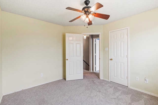 unfurnished bedroom featuring baseboards, light colored carpet, and ceiling fan