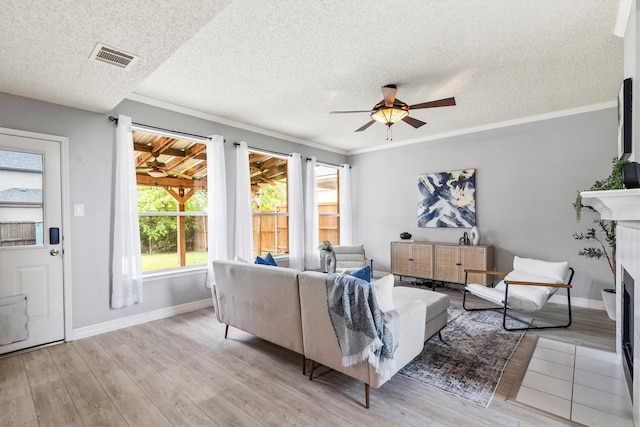 living area with visible vents, a ceiling fan, light wood-style flooring, and a fireplace
