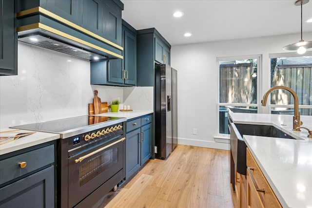 3219 Bryan St, Dallas, TX 75204 - kitchen featuring electric range, wall chimney range hood, light wood-style flooring, light countertops, and stainless steel fridge