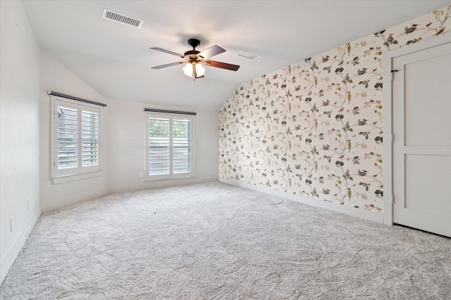 carpeted spare room with a ceiling fan, visible vents, baseboards, lofted ceiling, and wallpapered walls
