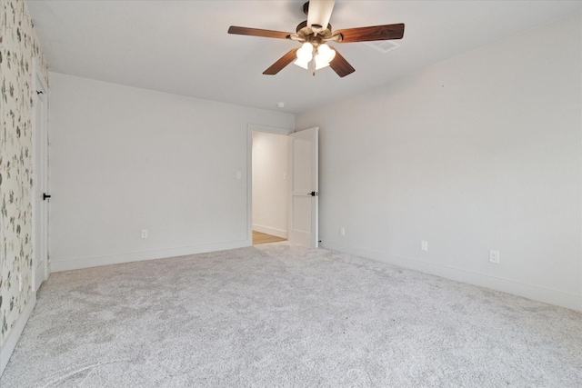 carpeted empty room featuring a ceiling fan and baseboards