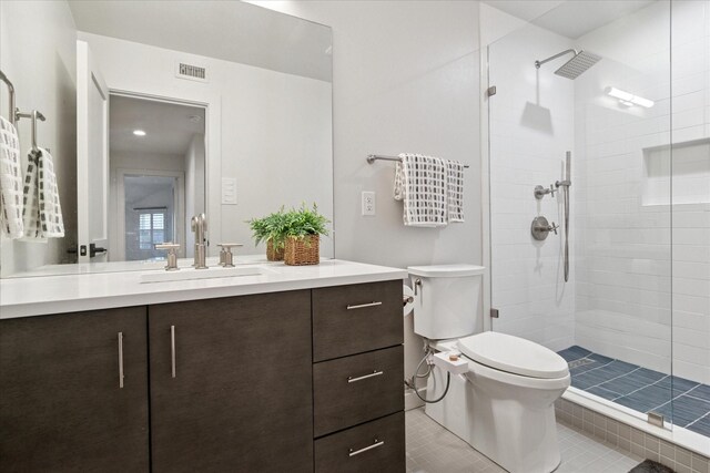 bathroom with toilet, visible vents, tiled shower, and tile patterned flooring