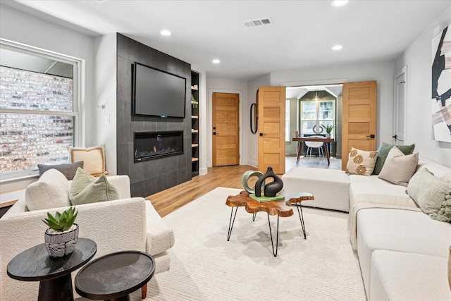 3219 Bryan St, Dallas, TX 75204 - living room with a tiled fireplace, light wood-style flooring, recessed lighting, and baseboards