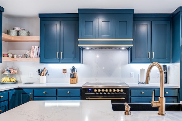 kitchen featuring stainless steel stove, blue cabinets, open shelves, and light stone countertops