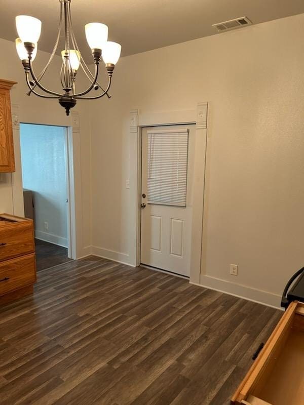 unfurnished dining area with visible vents, baseboards, dark wood-style floors, and a notable chandelier