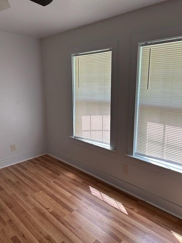 spare room with baseboards and light wood-style flooring